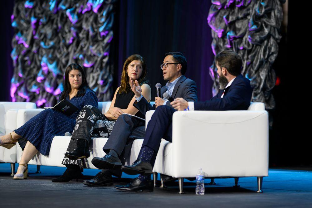 A panel of four speakers are seated on the mainstage for their spotlight session