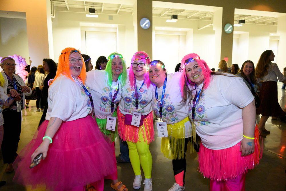 Attendees dressed in neon pose for a photo at the Montessori greenhouse themed dance party